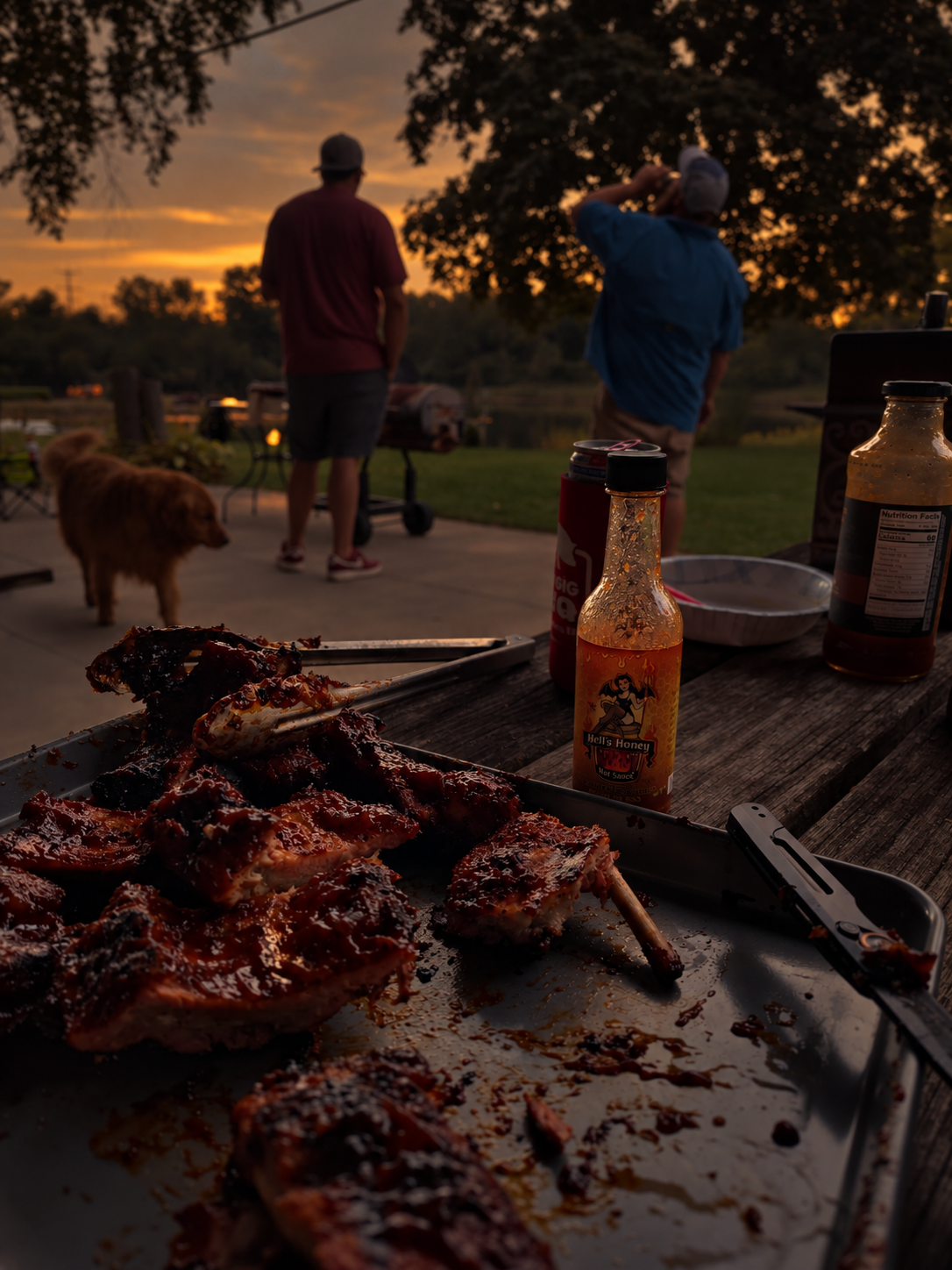 Backyard barbecue at sunset with Hell's Honey hot sauce on the table